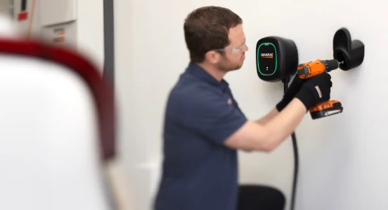 An electrician mounting a Generac Level 2 EV charger on a garage wall